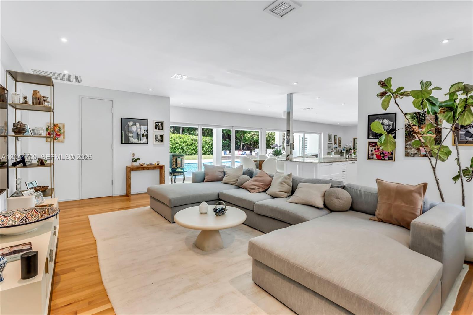 A living room features a large gray sectional sofa, a round coffee table, and hardwood floors — 12121 SW 64th Ave, Pinecrest FL 33156, PINECREST, FL