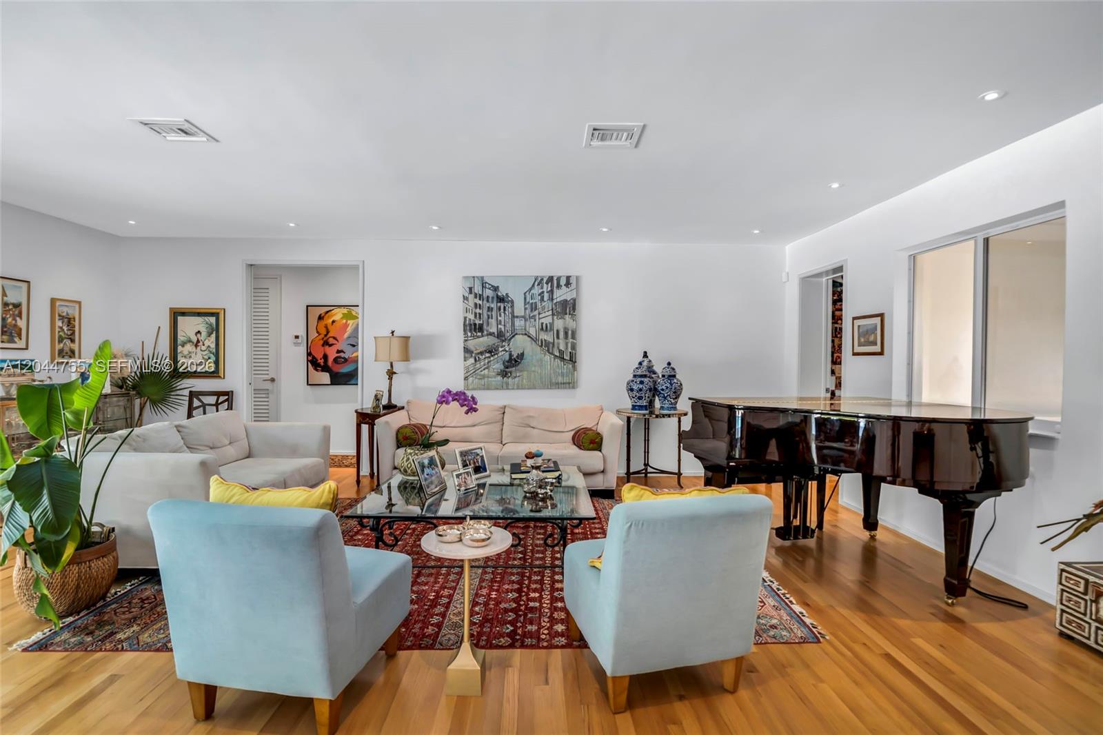 A living room features a grand piano, light blue armchairs, a sofa, and a patterned rug — 12121 SW 64th Ave, Pinecrest FL 33156, PINECREST, FL
