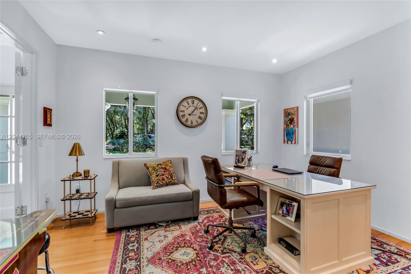A home office features a desk, leather chair, sofa, wall clock, and a patterned area rug — 12121 SW 64th Ave, Pinecrest FL 33156, PINECREST, FL