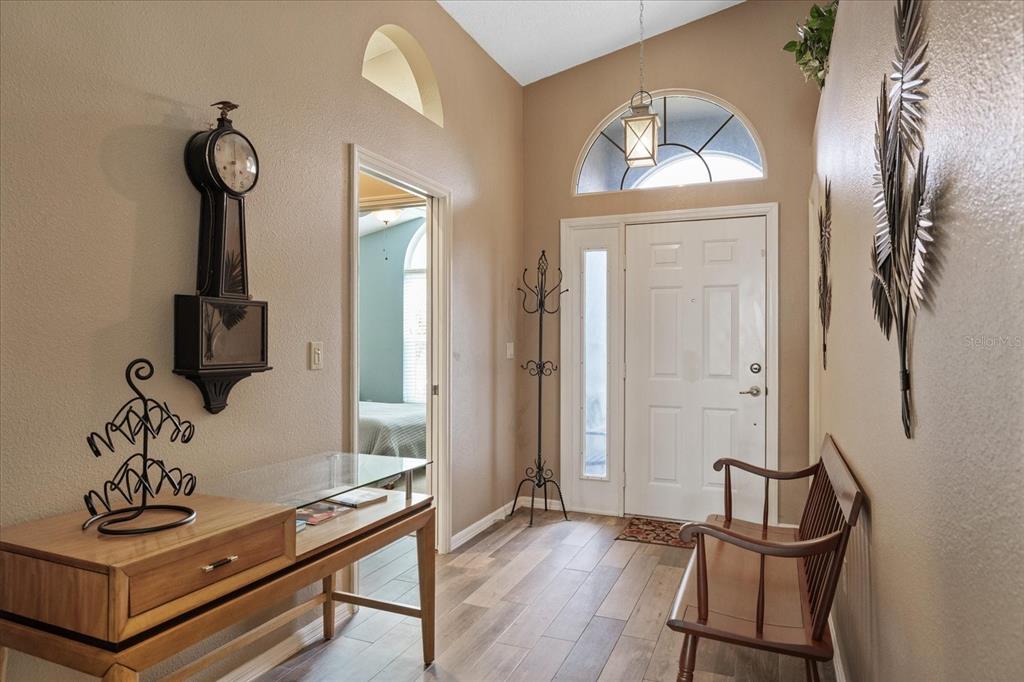 An entryway features a wooden console table, a wall clock, a bench, and tile flooring — 3251 SCORECARD DRIVE, NEW PORT RICHEY, FL