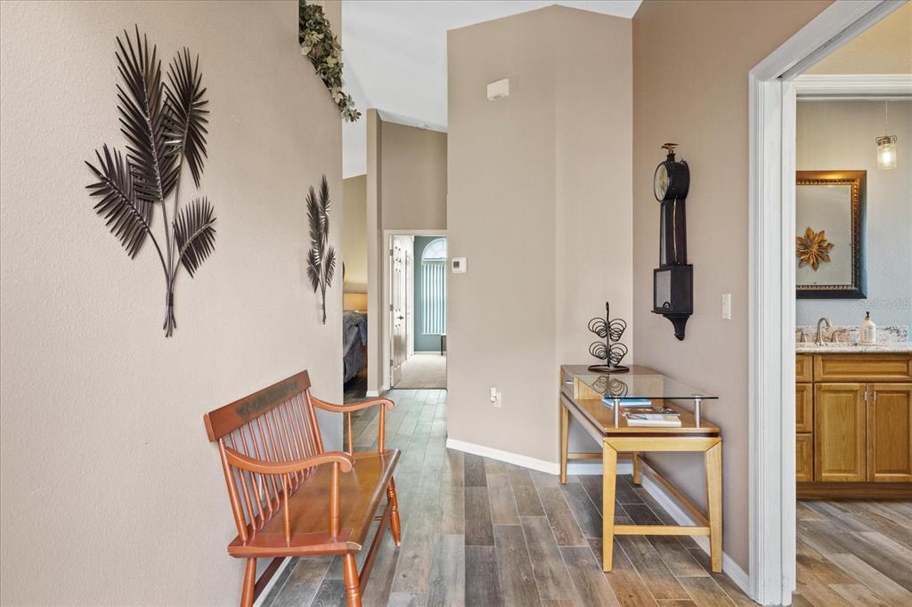 A hallway with wood-look tile flooring, a wooden bench, a console table, and wall decor — 3251 SCORECARD DRIVE, NEW PORT RICHEY, FL
