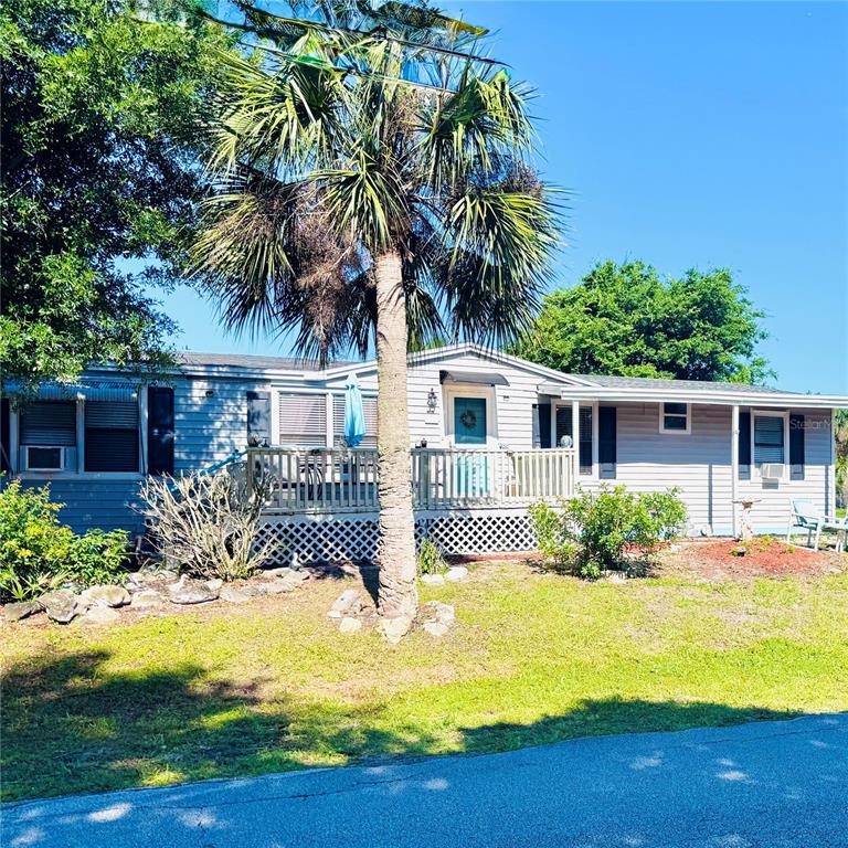 A light blue single-story mobile home features a wooden deck and a prominent palm tree — 1301 AVENUE D, ORMOND BEACH, FL