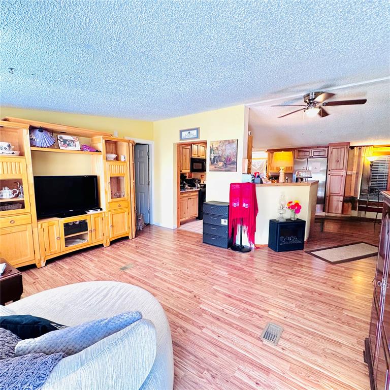 A living room with wood-look flooring, a large entertainment center, and an open kitchen — 1301 AVENUE D, ORMOND BEACH, FL