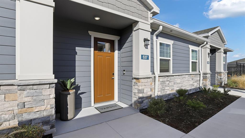 The exterior of a gray-sided house features a brown front door and stone veneer base — 2507 KOJI STREET UNIT Aspire, MOUNT DORA, FL