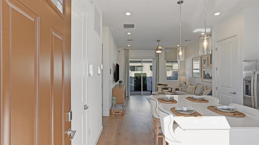 An open-concept living and dining area features light wood floors, white cabinetry, and pendant lighting — 2507 KOJI STREET UNIT Aspire, MOUNT DORA, FL
