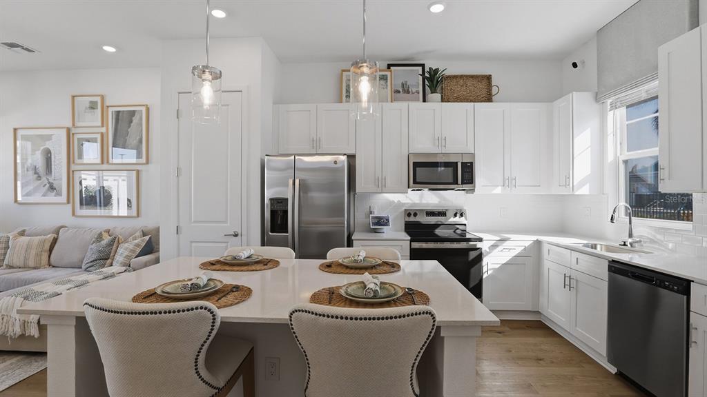 A modern kitchen features white cabinetry, stainless steel appliances, and a large central island — 2507 KOJI STREET UNIT Aspire, MOUNT DORA, FL