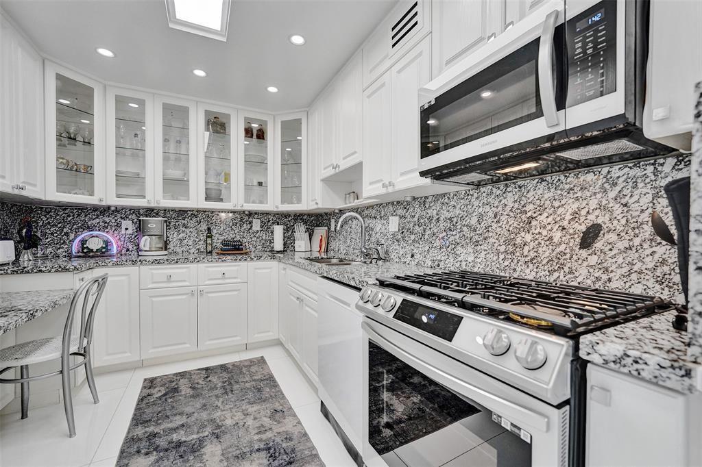 A kitchen features white cabinets, granite countertops, a gas range, and a built-in microwave — 2030 S Ocean Drive # 510, Hallandale Beach FL 33009, HALLANDALE BEACH, FL