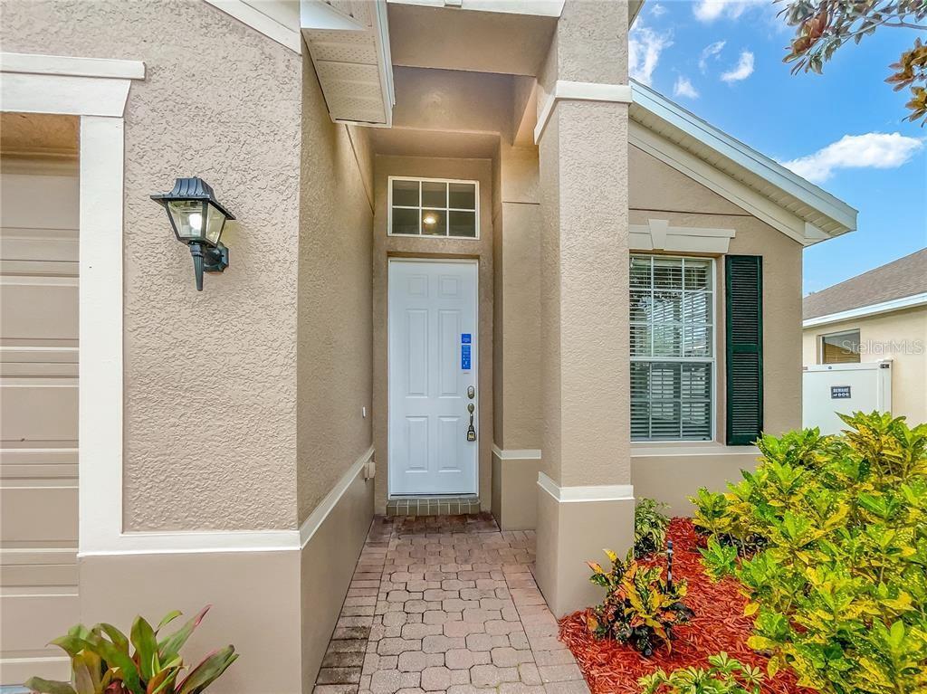 The exterior of a house features a white front door, a brick walkway, and landscaping — 2248 STONE LAKE COURT, ORLANDO, FL