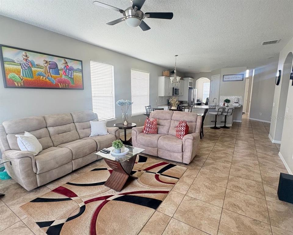 A living room with beige furniture and a patterned rug opens into a kitchen area — 2248 STONE LAKE COURT, ORLANDO, FL