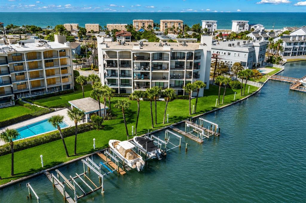 A boat is lifted on a mechanical dock system over clear blue water — 9825 HARRELL AVENUE UNIT 404, TREASURE ISLAND, FL