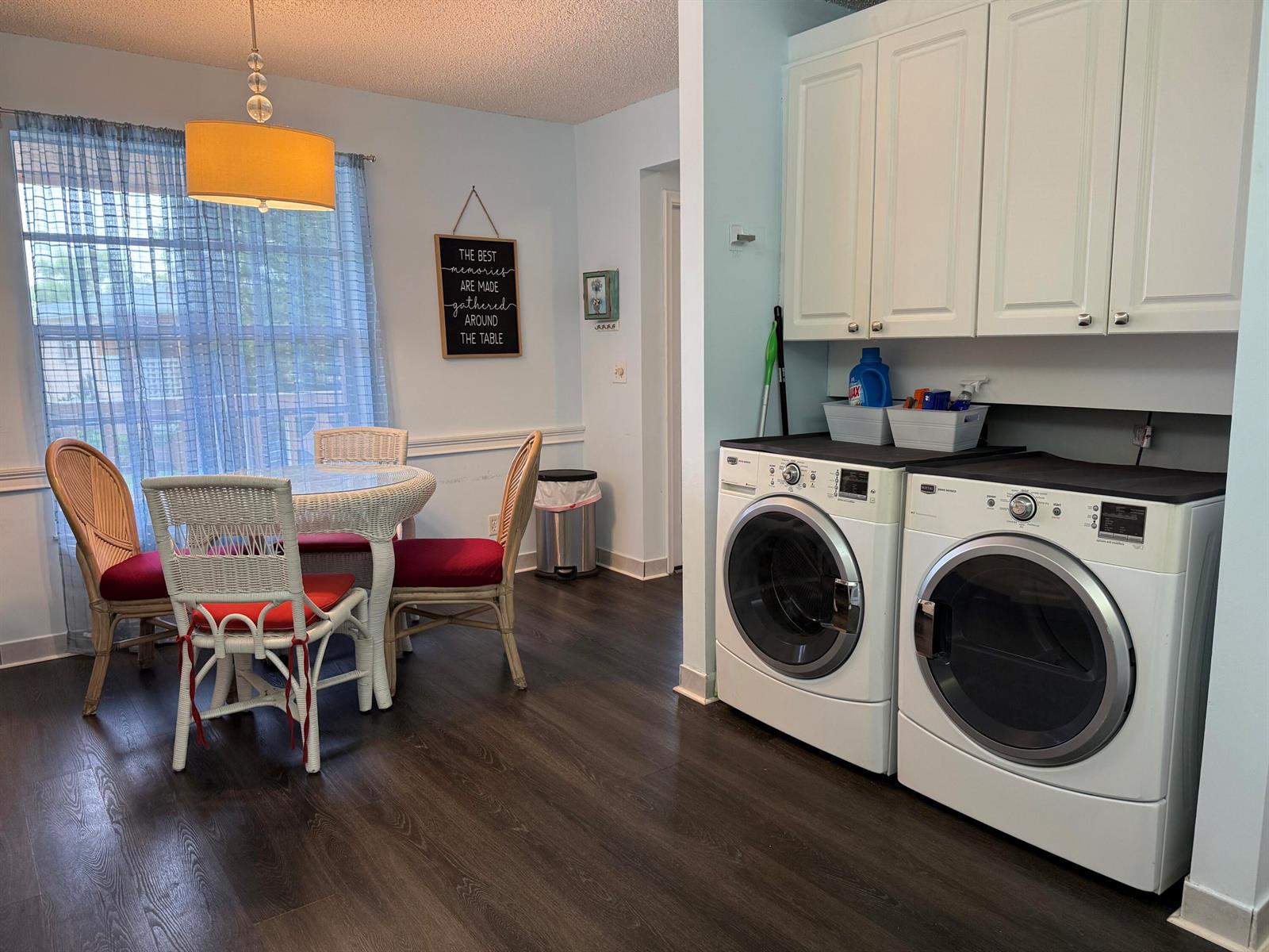 A dining area with a wicker table set next to a laundry space with white appliances — 1520 NW 19th Terrace # 203, Delray Beach FL 33445, DELRAY BEACH, FL