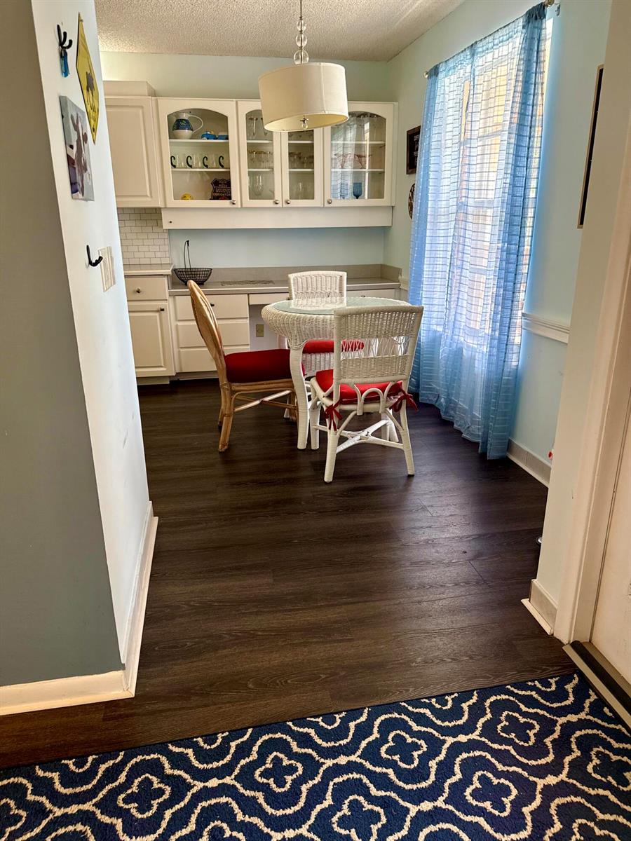 A dining area features a white wicker table and chairs, dark flooring, and white cabinetry — 1520 NW 19th Terrace # 203, Delray Beach FL 33445, DELRAY BEACH, FL