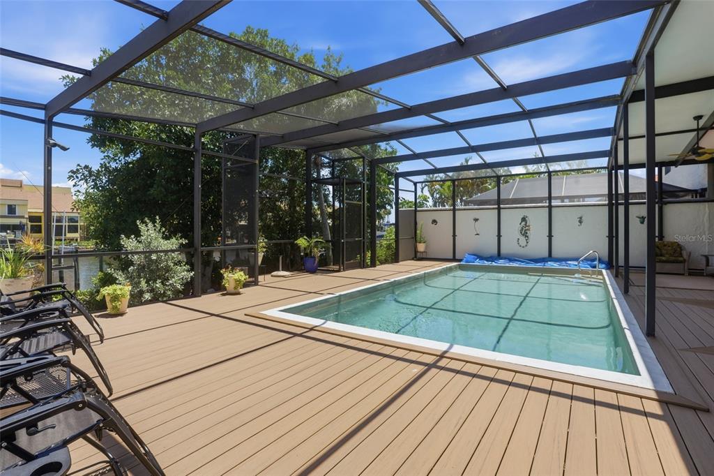 A screened-in pool deck features wood-look decking, lounge chairs, and a view of the water — 25188 MARION AVENUE UNIT 10, PUNTA GORDA, FL