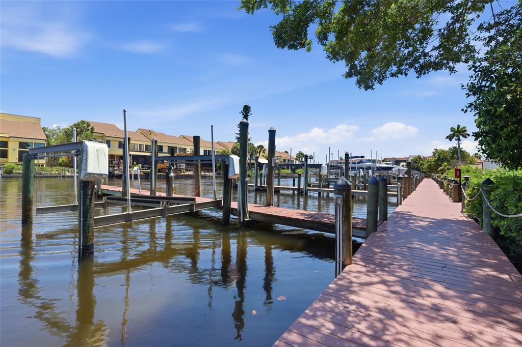 A wooden dock extends along a canal with several boat lifts and residential buildings nearby — 25188 MARION AVENUE UNIT 10, PUNTA GORDA, FL