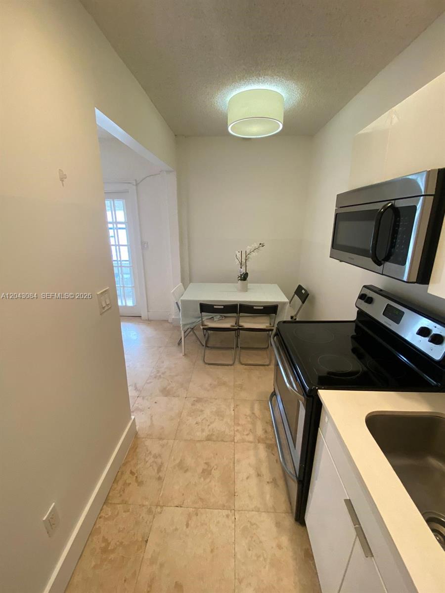 A kitchen features tile flooring, a dining table with chairs, and stainless steel appliances — 934 Michigan Ave # 308, Miami Beach FL 33139, MIAMI BEACH, FL