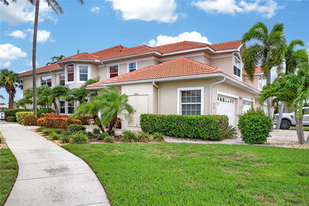 A two-story tan house with a red tile roof and a paved driveway — 2590 TARPON COVE DRIVE UNIT 821, PUNTA GORDA, FL