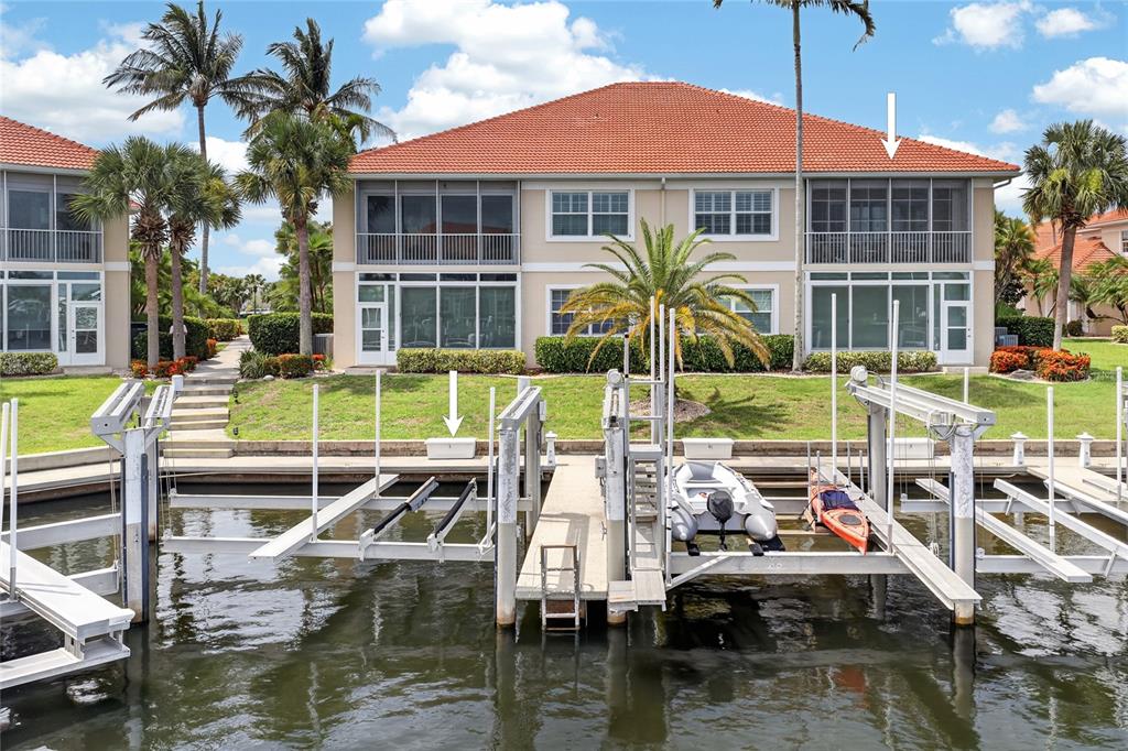 A two-story building with a tiled roof sits behind a boat dock on a canal — 2590 TARPON COVE DRIVE UNIT 821, PUNTA GORDA, FL