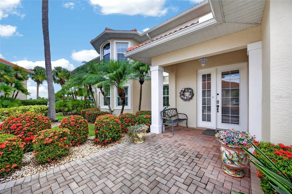 A paved entryway leads to a double-door entrance with a bench and potted flowers — 2590 TARPON COVE DRIVE UNIT 821, PUNTA GORDA, FL