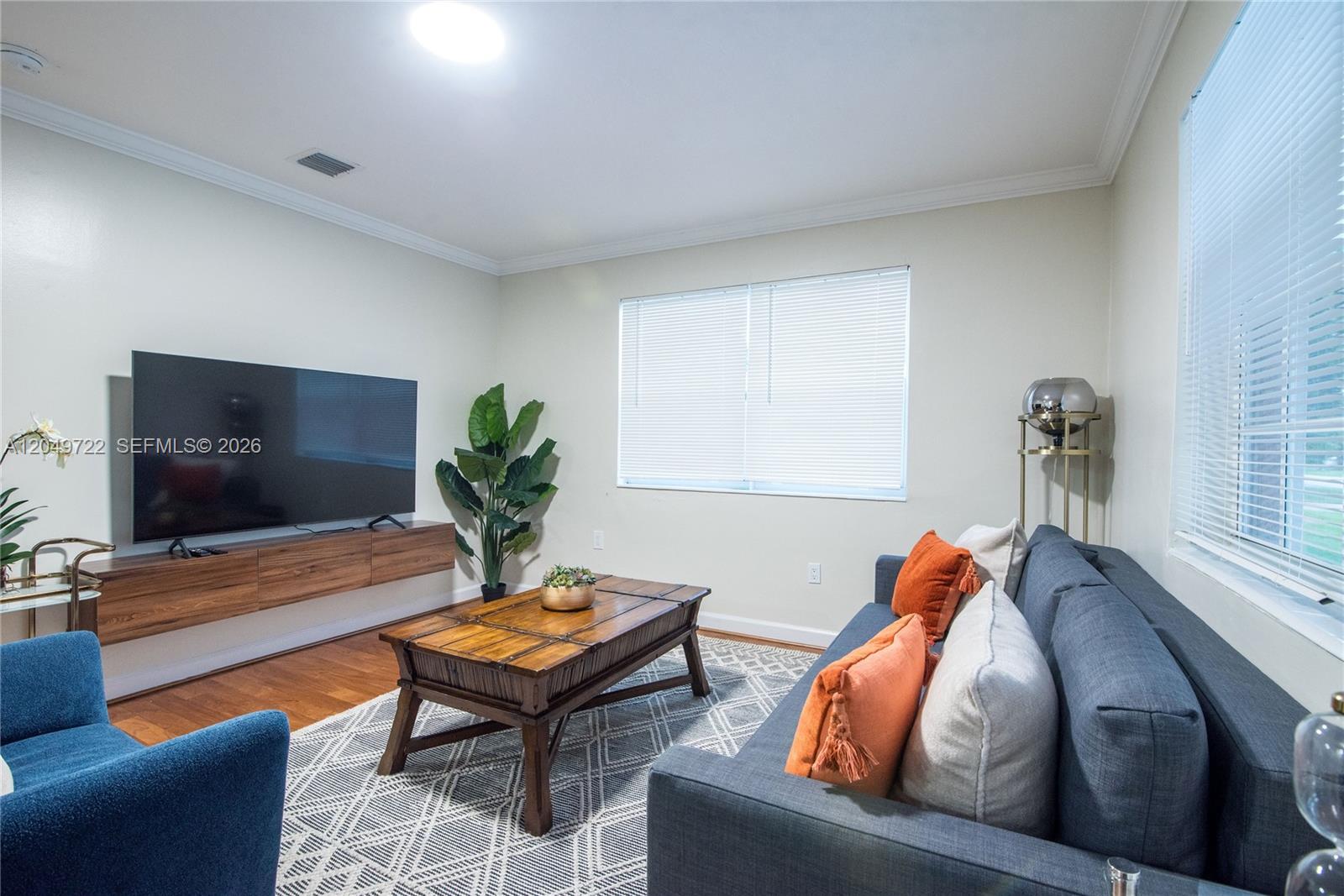 A living room features a wall-mounted wooden media console, a dark sofa, and a coffee table — 2270 Havana Dr, Miramar FL 33023, MIRAMAR, FL