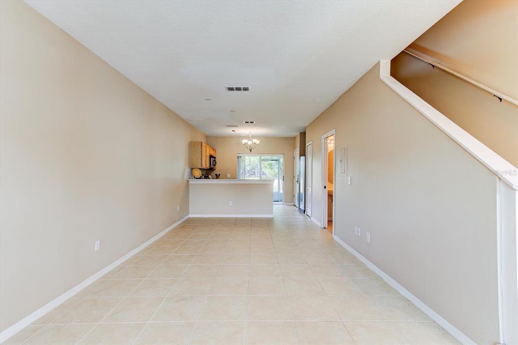 An open-concept living area with beige tile flooring leads to a kitchen with a breakfast bar — 509 WILTON CIRCLE, SANFORD, FL