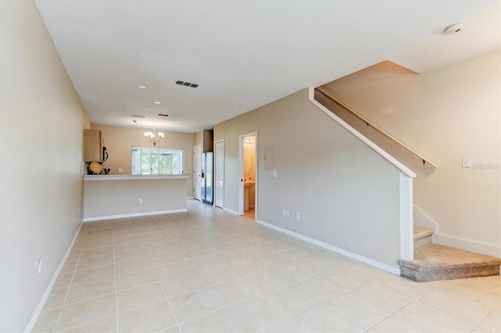 An open-concept living area features tile flooring, a kitchen breakfast bar, and a carpeted staircase — 509 WILTON CIRCLE, SANFORD, FL