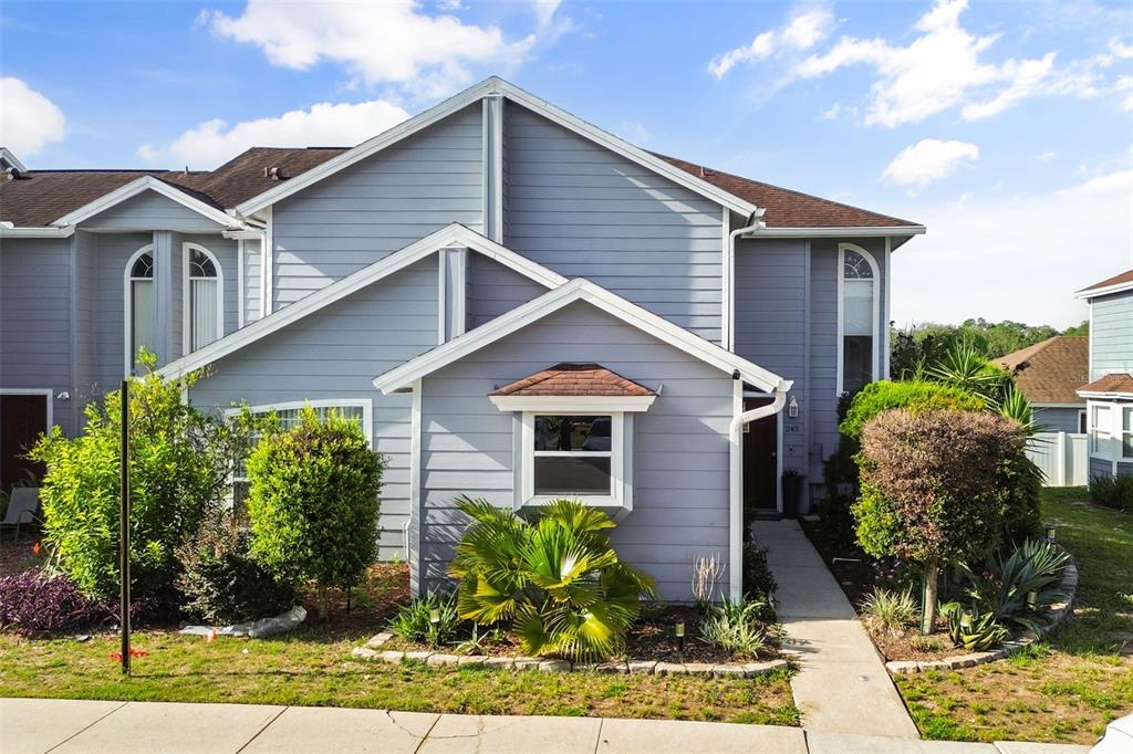 A two-story blue-sided townhouse features a front garden, a bay window, and a walkway — 245 MANGO DRIVE, DAVENPORT, FL