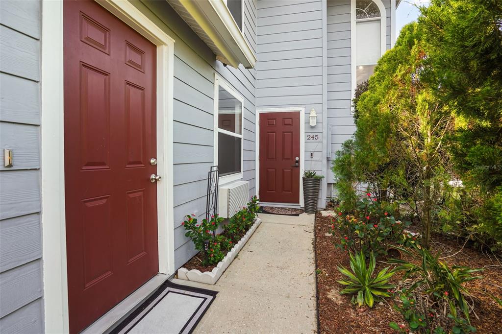 A concrete walkway leads to two red front doors on a light blue house exterior — 245 MANGO DRIVE, DAVENPORT, FL