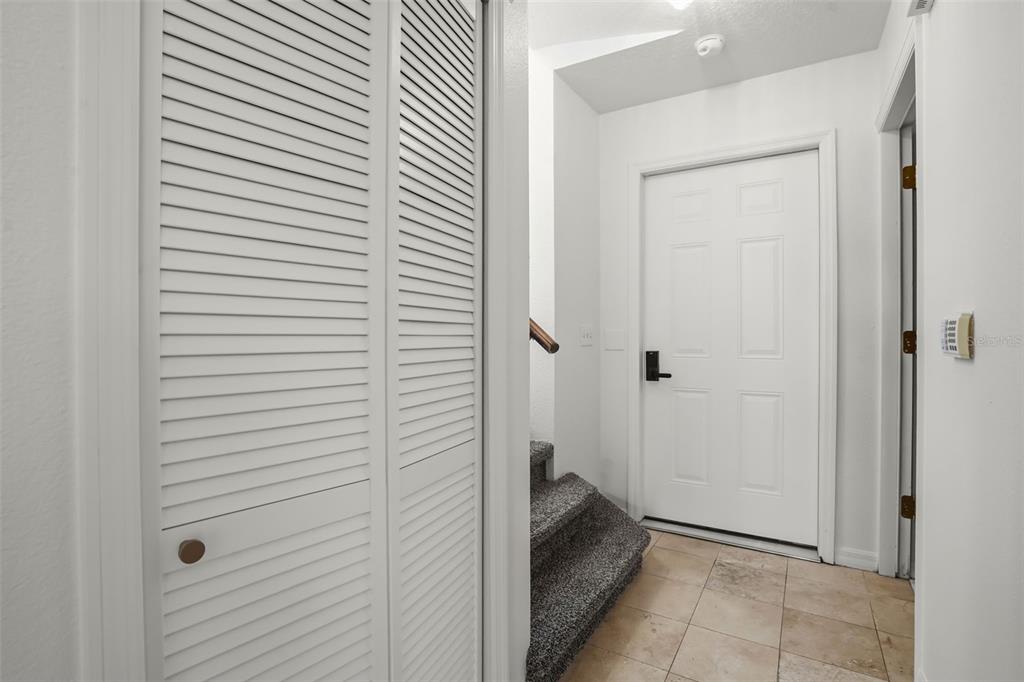 An interior view shows a tiled entryway with a louvered closet door and carpeted stairs — 245 MANGO DRIVE, DAVENPORT, FL