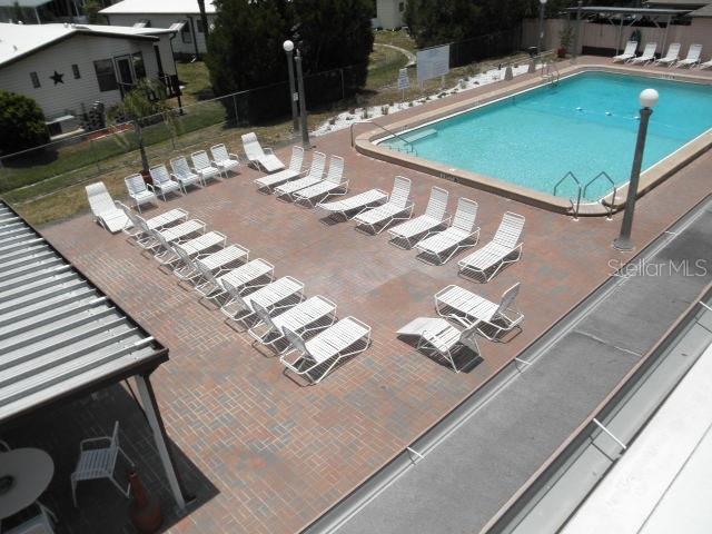 An elevated view of a swimming pool area with numerous lounge chairs on a brick patio — 5096 PALENA BOULEVARD, NORTH PORT, FL