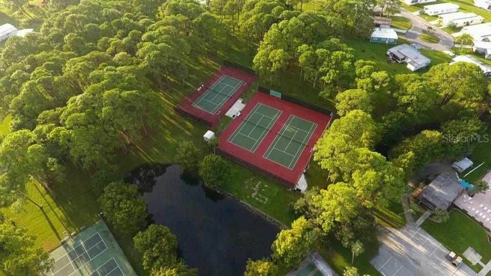 An aerial view shows multiple tennis courts surrounded by trees and a small pond — 5096 PALENA BOULEVARD, NORTH PORT, FL