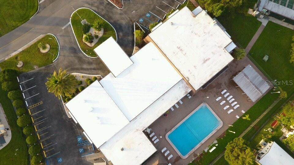 An aerial view shows a building with a white roof, a swimming pool, and parking — 5096 PALENA BOULEVARD, NORTH PORT, FL