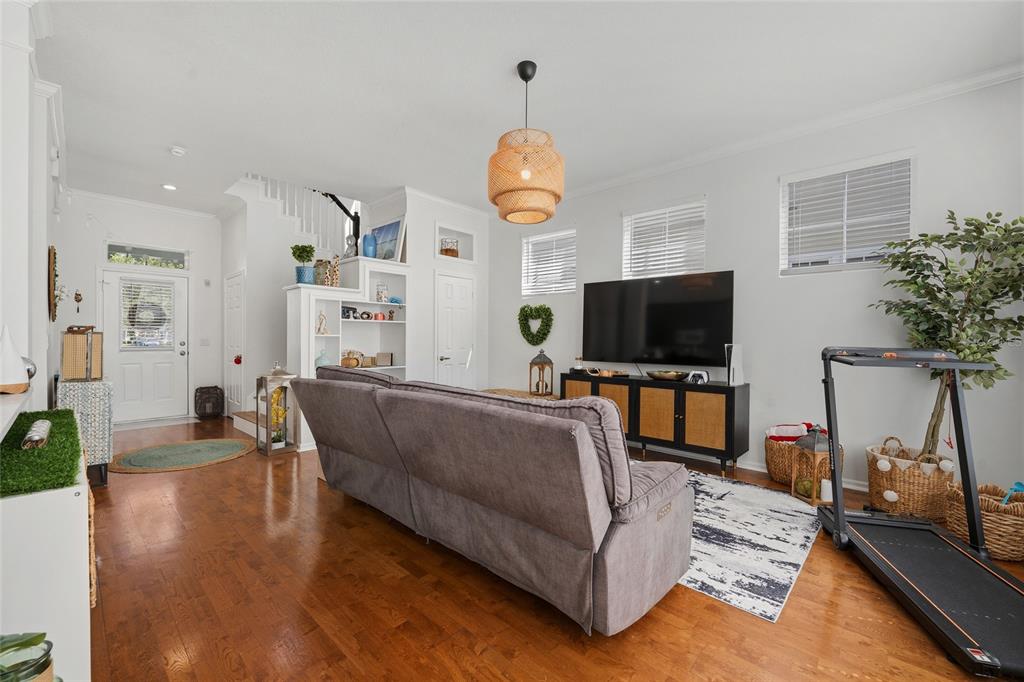 A living room features hardwood floors, a gray sofa, a television console, and a treadmill — 181 LONGVIEW AVE, KISSIMMEE, FL