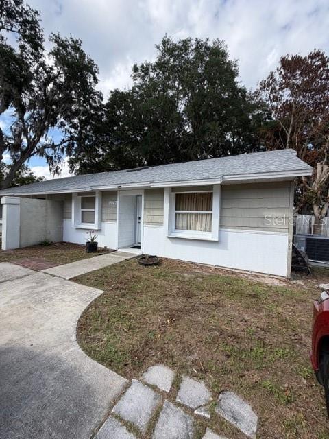A single-story house with a light-colored exterior, a gray shingled roof, and a concrete driveway — 9943 BURL WAY, ORLANDO, FL