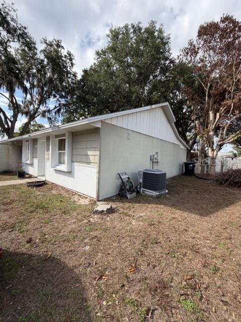 The exterior side of a light-colored house features a central air conditioning unit — 9943 BURL WAY, ORLANDO, FL