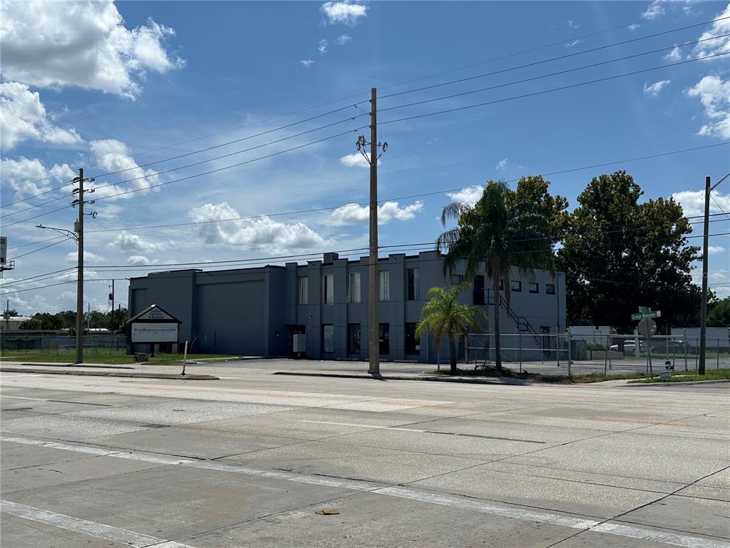A two-story gray commercial building stands behind a parking lot under a blue sky — 2300 S ORANGE BLOSSOM TRAIL, ORLANDO, FL