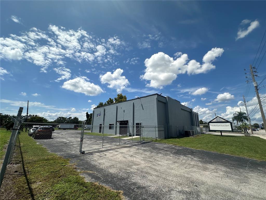 A gray commercial building with a fenced parking lot under a blue sky — 2300 S ORANGE BLOSSOM TRAIL, ORLANDO, FL