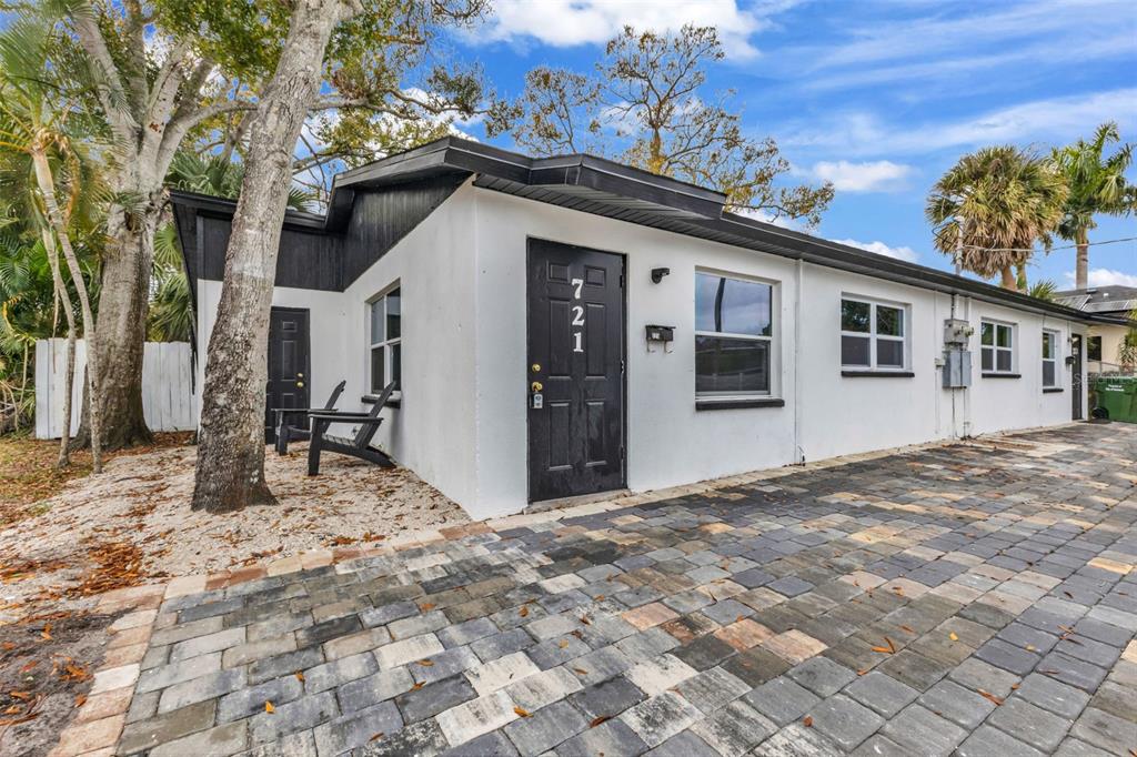 A white single-story building with black trim and doors features a paved stone driveway — 721 N OSPREY AVENUE, SARASOTA, FL