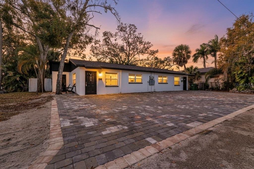 A single-story white house with a paved driveway and dark trim at sunset — 721 N OSPREY AVENUE, SARASOTA, FL