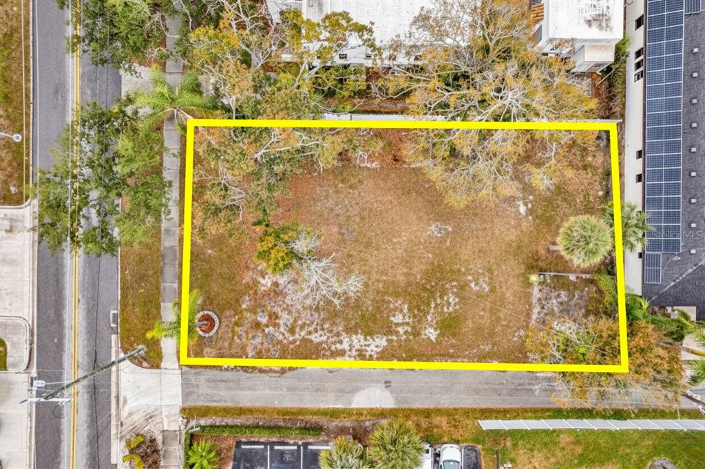 An aerial view shows a rectangular vacant lot outlined in yellow near a paved road — 721 N OSPREY AVENUE, SARASOTA, FL