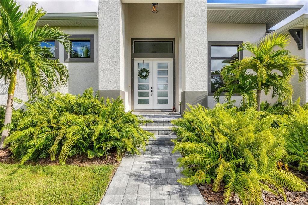 A paved walkway leads to the white double front doors of a modern stucco home — 0 SYMCO AVENUE, NORTH PORT, FL