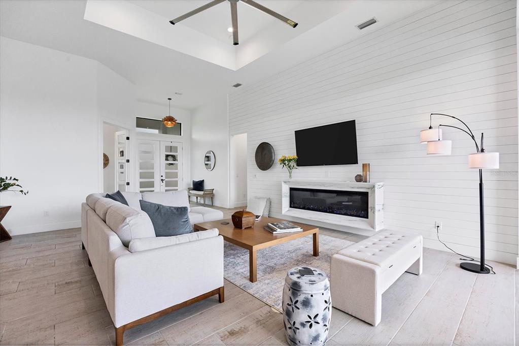 A bright living room features a white shiplap wall, a fireplace, and a sectional sofa — 0 SYMCO AVENUE, NORTH PORT, FL