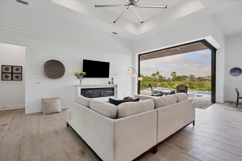A living room features a white shiplap wall, a fireplace, and sliding doors opening to a pool — 0 SYMCO AVENUE, NORTH PORT, FL