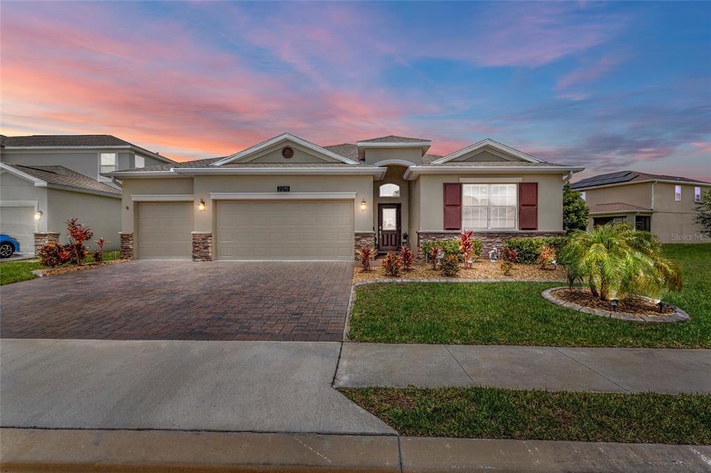 A single-story suburban house features a tan stucco exterior, stone accents, and a paved driveway — 2215 CAMDEN PARK AVENUE, DAVENPORT, FL