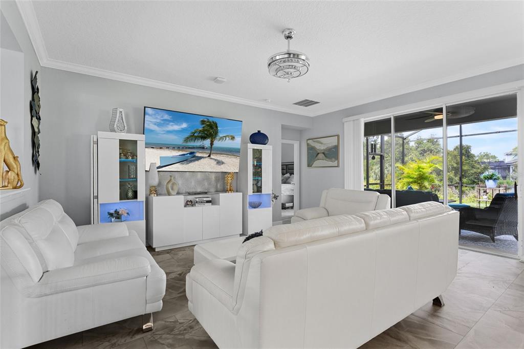 A living room features white leather sofas, a media console, and sliding doors to a patio — 2215 CAMDEN PARK AVENUE, DAVENPORT, FL