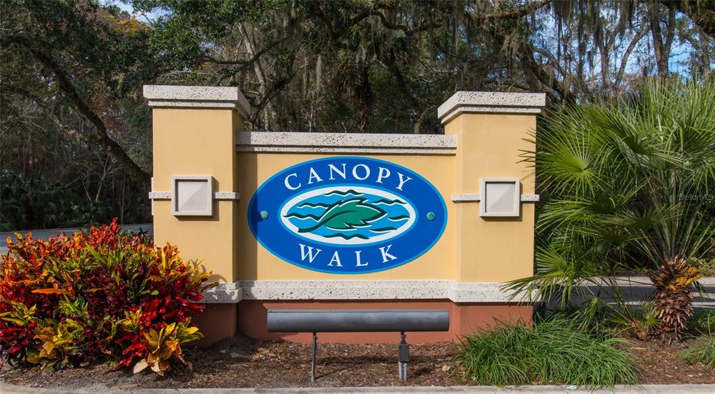 A beige monument sign for Canopy Walk stands outdoors surrounded by trees and landscaping — 1100 CANOPY WALK LANE UNIT 1113, PALM COAST, FL