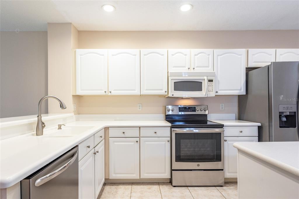 A kitchen with white cabinets, stainless steel appliances, and light-colored countertops — 1100 CANOPY WALK LANE UNIT 1113, PALM COAST, FL