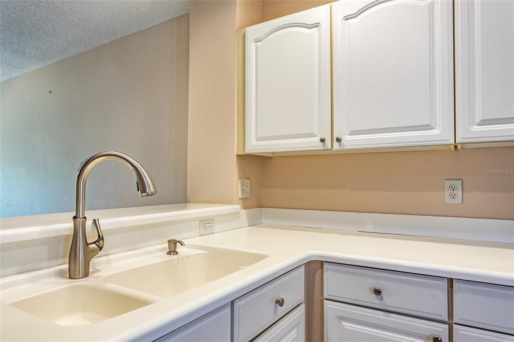 A kitchen features white cabinets, a double-basin sink, and a stainless steel faucet — 1100 CANOPY WALK LANE UNIT 1113, PALM COAST, FL