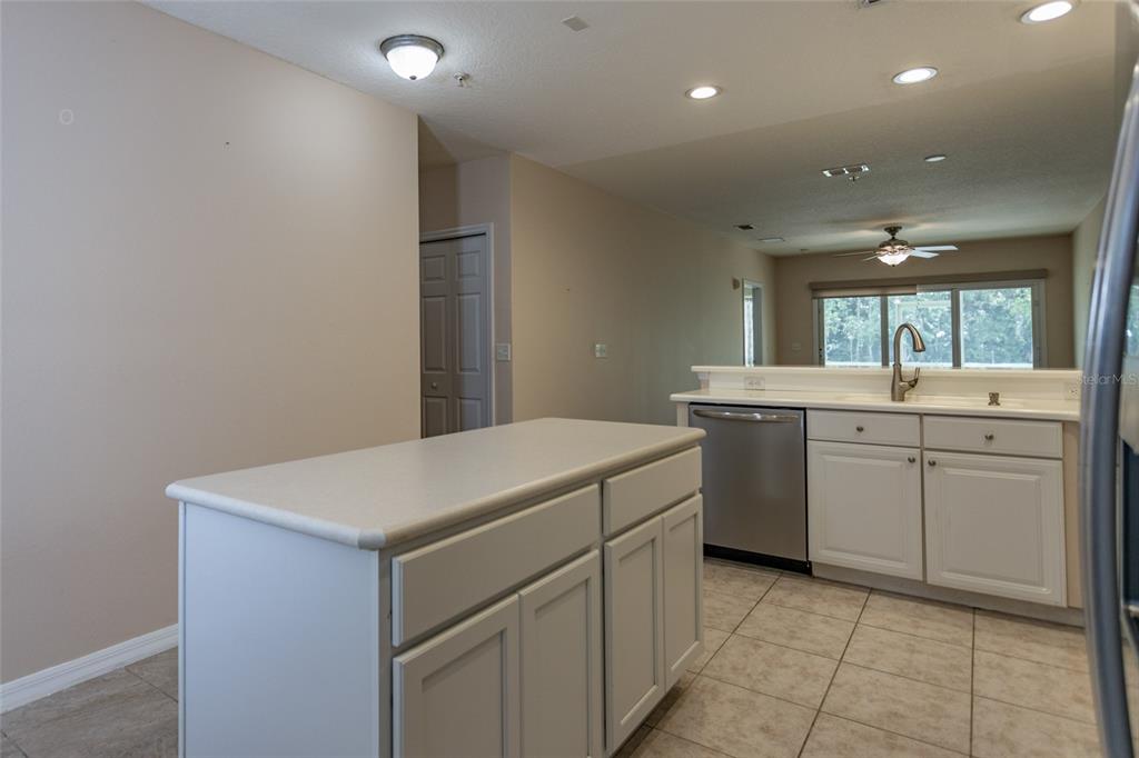 A kitchen with white cabinets, a central island, stainless steel dishwasher, and beige tile flooring — 1100 CANOPY WALK LANE UNIT 1113, PALM COAST, FL