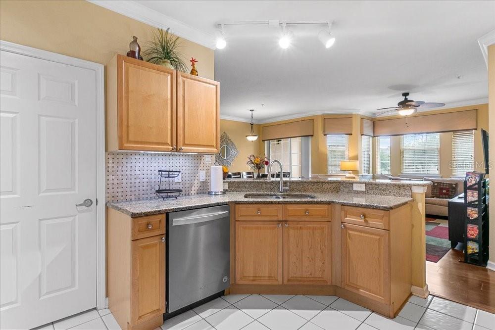 A kitchen with light wood cabinets, granite countertops, a stainless steel dishwasher, and tile flooring — 110 TERRACE RIDGE CIRCLE UNIT 110, DAVENPORT, FL