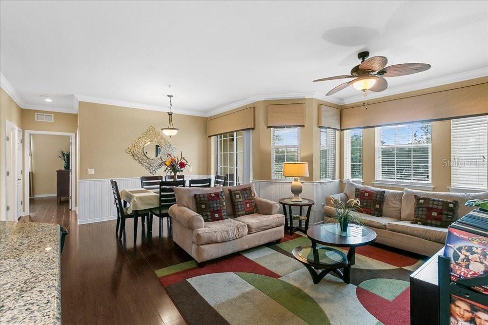 An open-concept living and dining area features hardwood floors, a ceiling fan, and large windows — 110 TERRACE RIDGE CIRCLE UNIT 110, DAVENPORT, FL